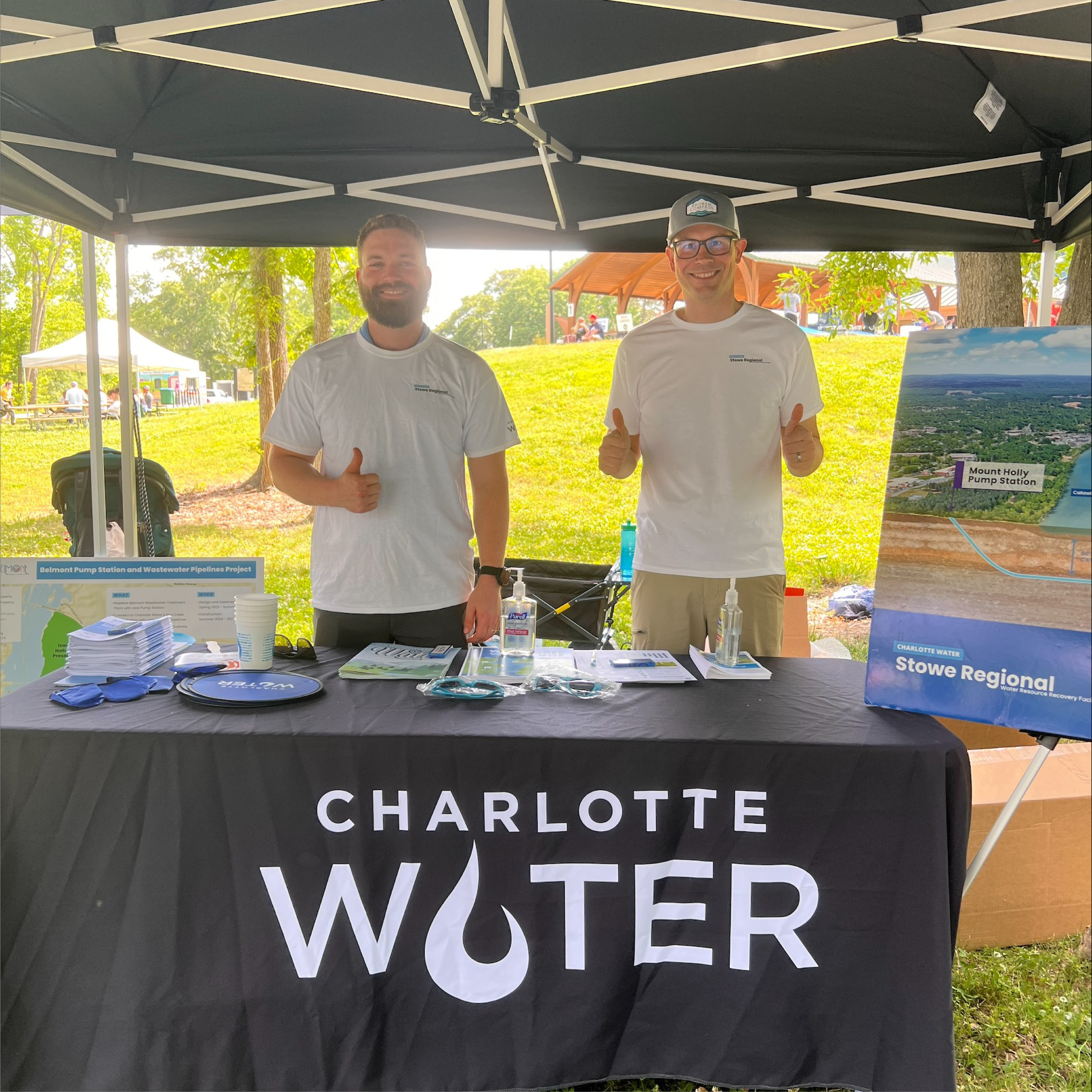 Two men give thumbs up at a Charlotte Water table