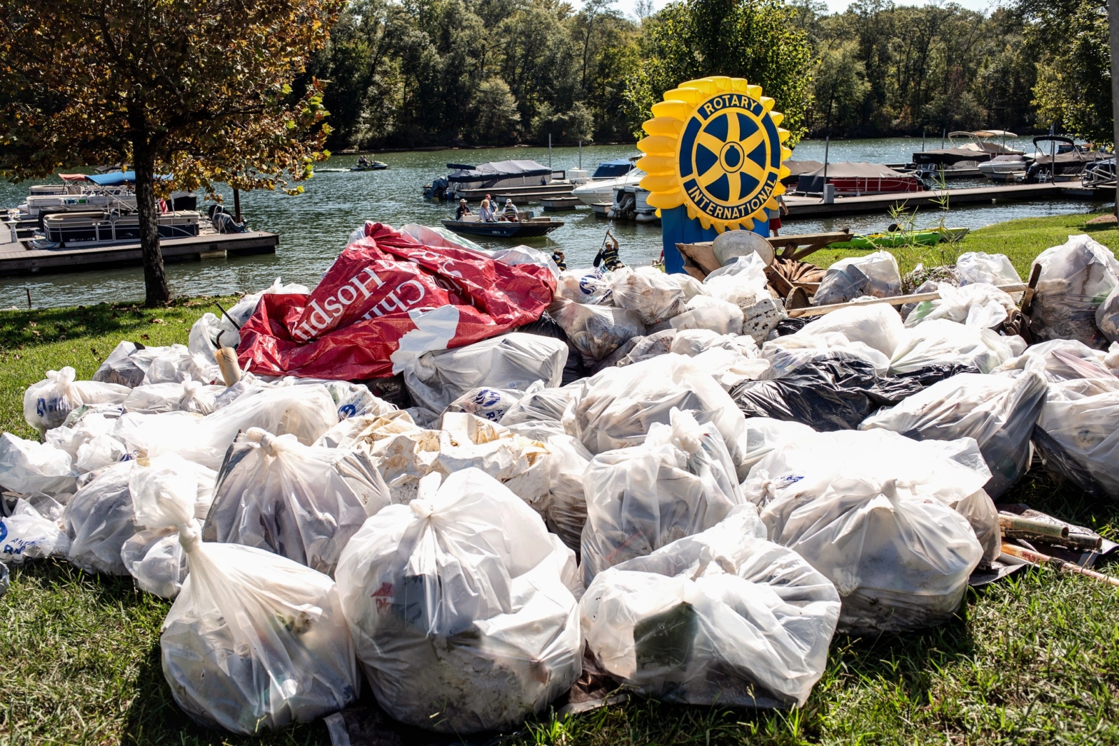 dozens of bags of garbage line the riverbank