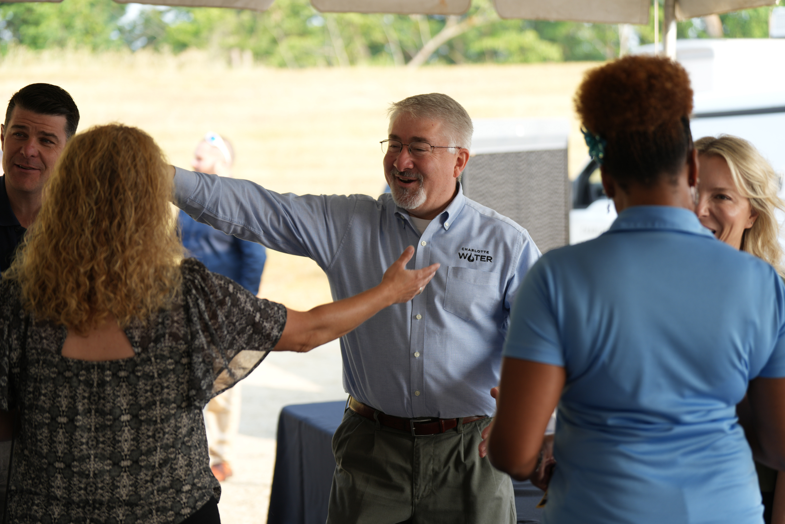 Charlotte water team and local community member discuss something enthusiastically with their hands gesturing in the air