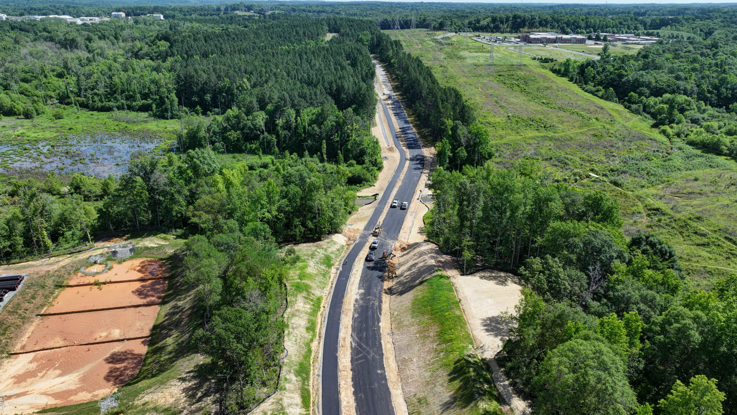 Paved access road and greenway lined with trees.