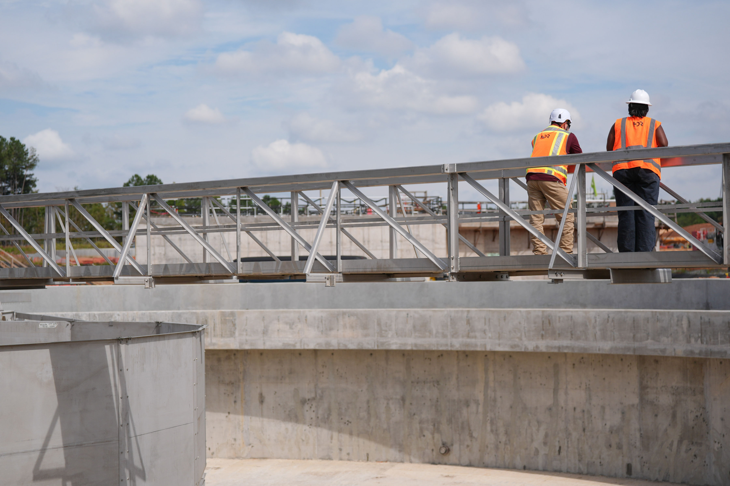 Two construction workers overlook the site from a scaffold.