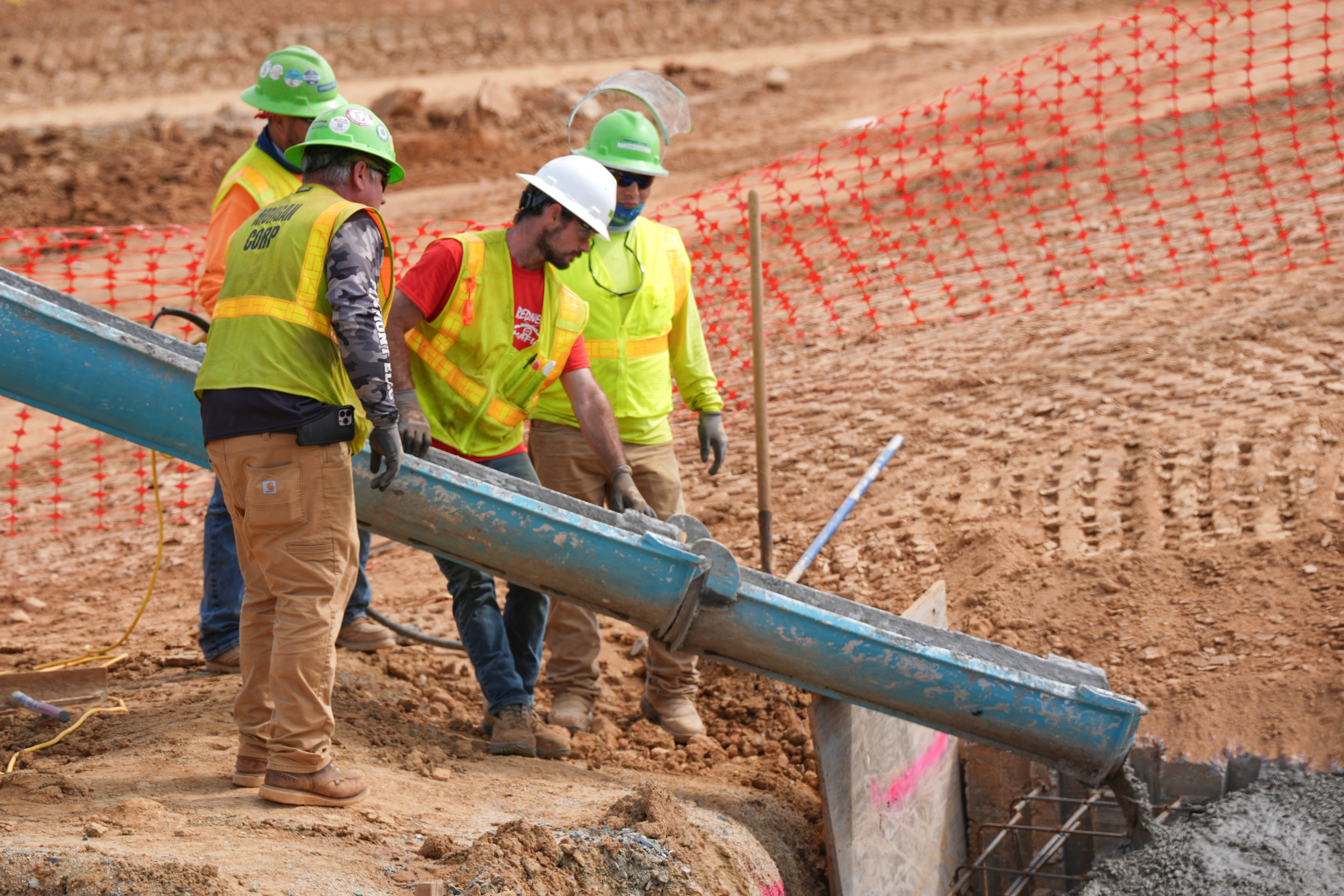 Four construction workers oversee a concrete pour.