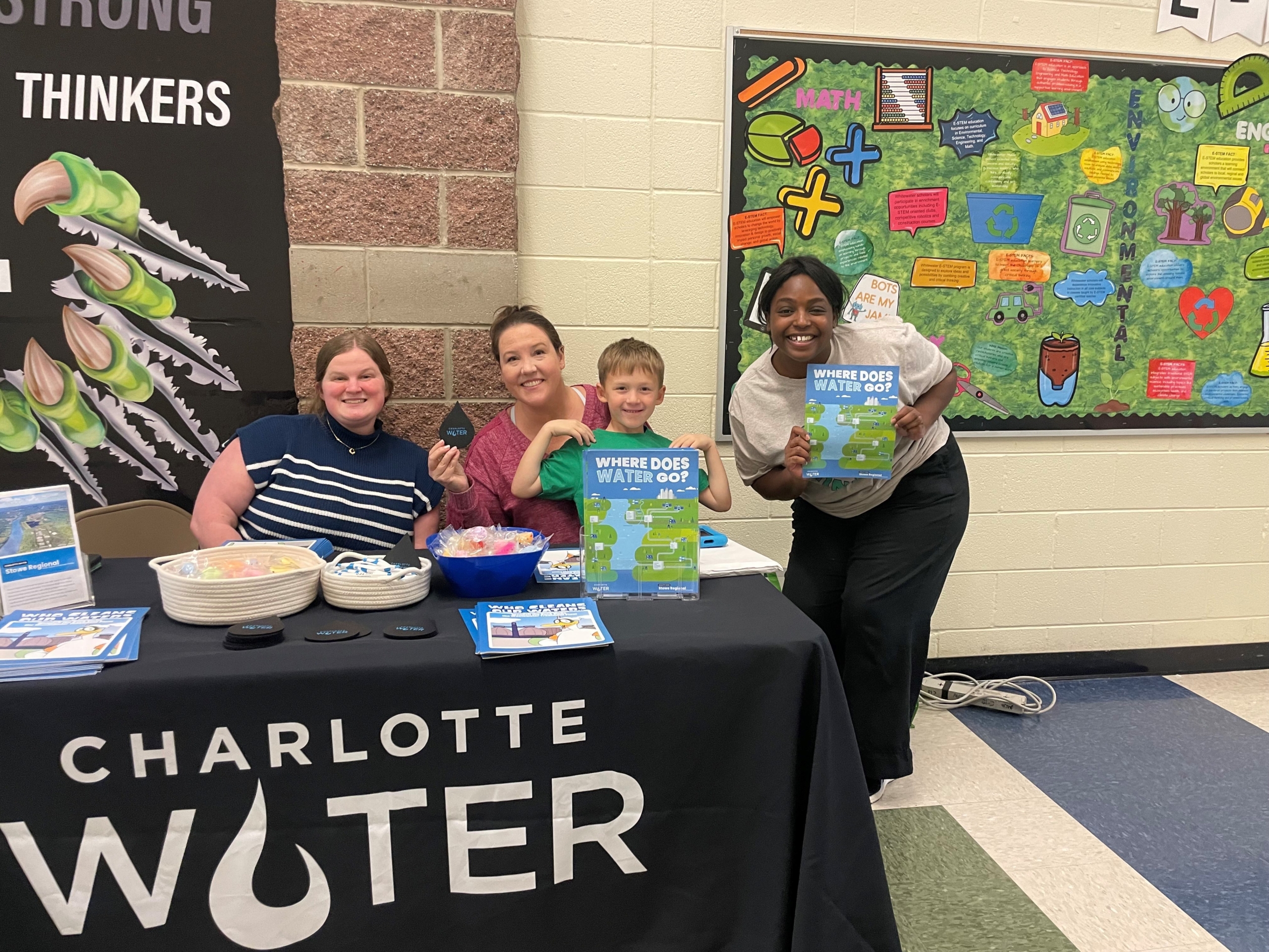 Three women and a child sitting at a Charlotte Water table with brochures.