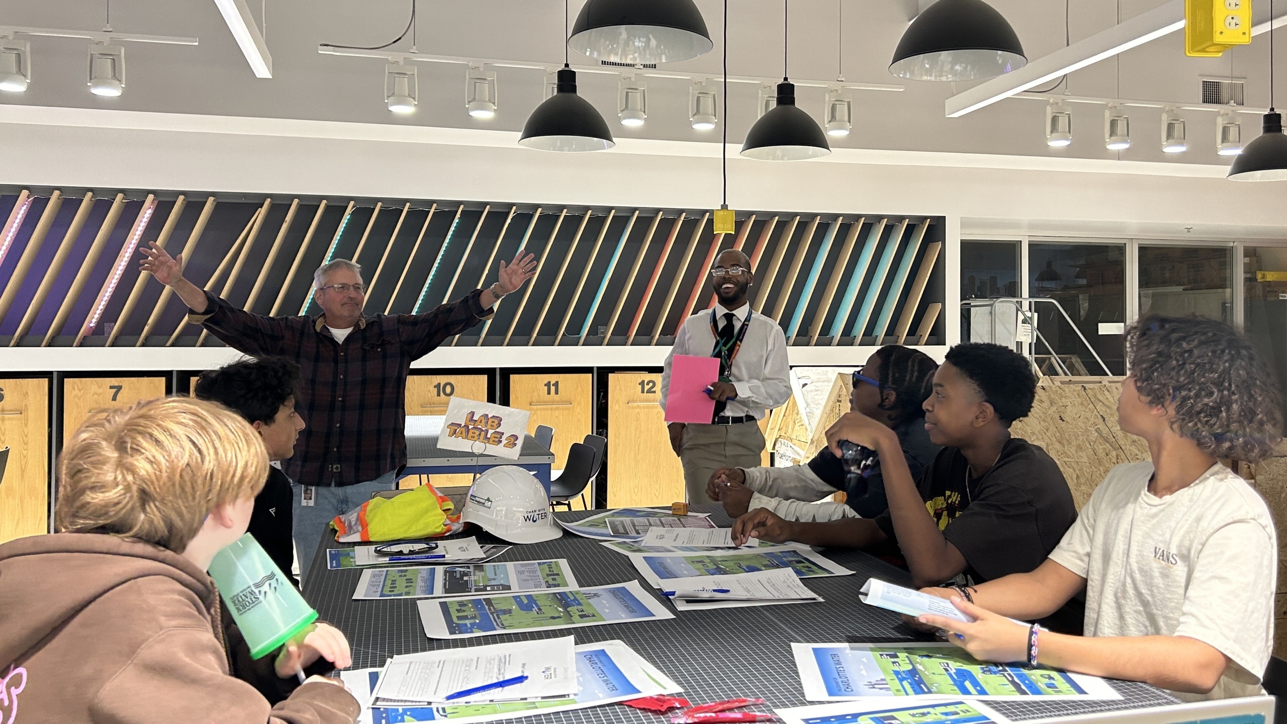 A Charlotte Water Employee presents to a table of middle school students