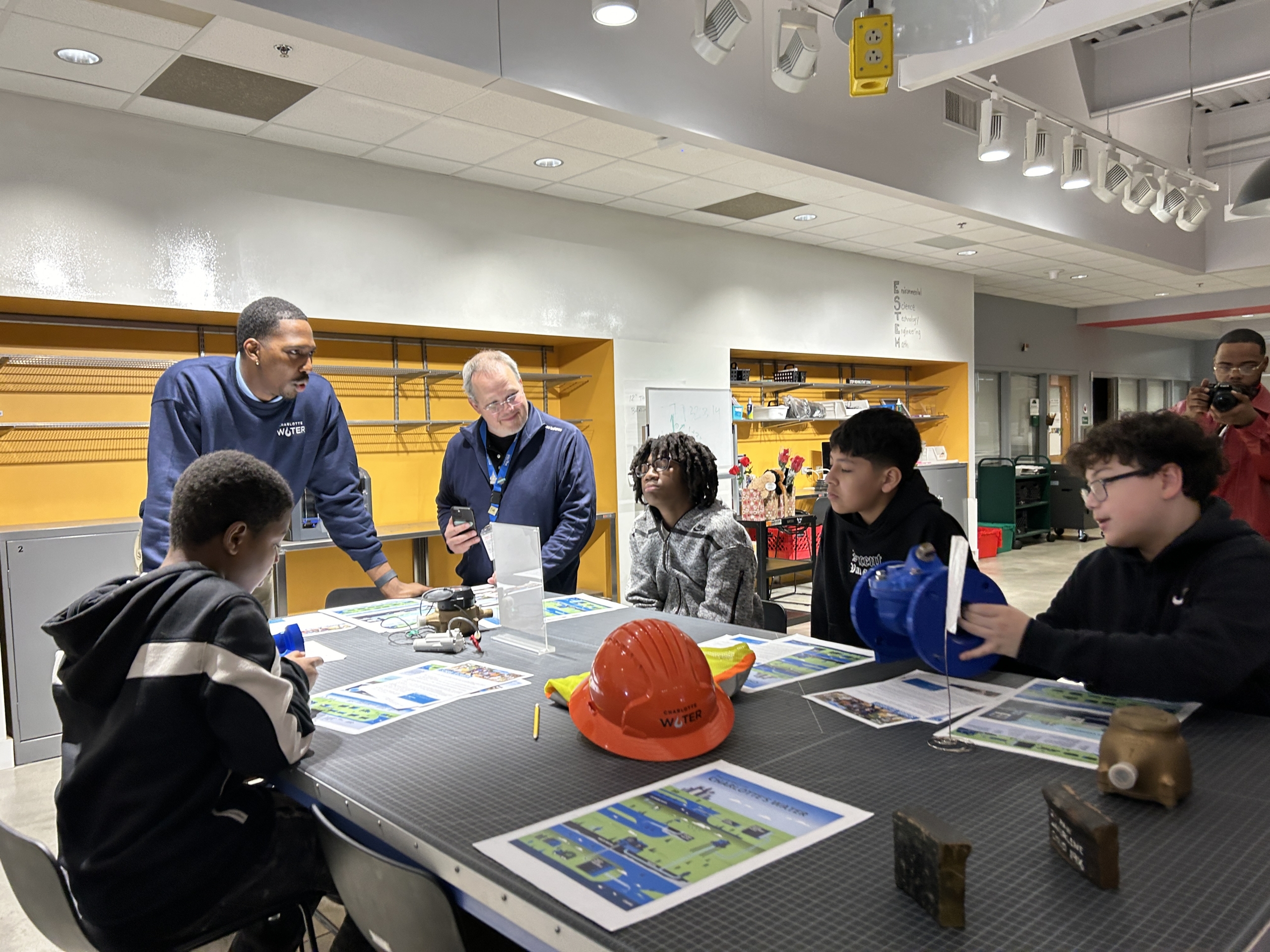 Students around a lab table talk to two Charlotte Water employees