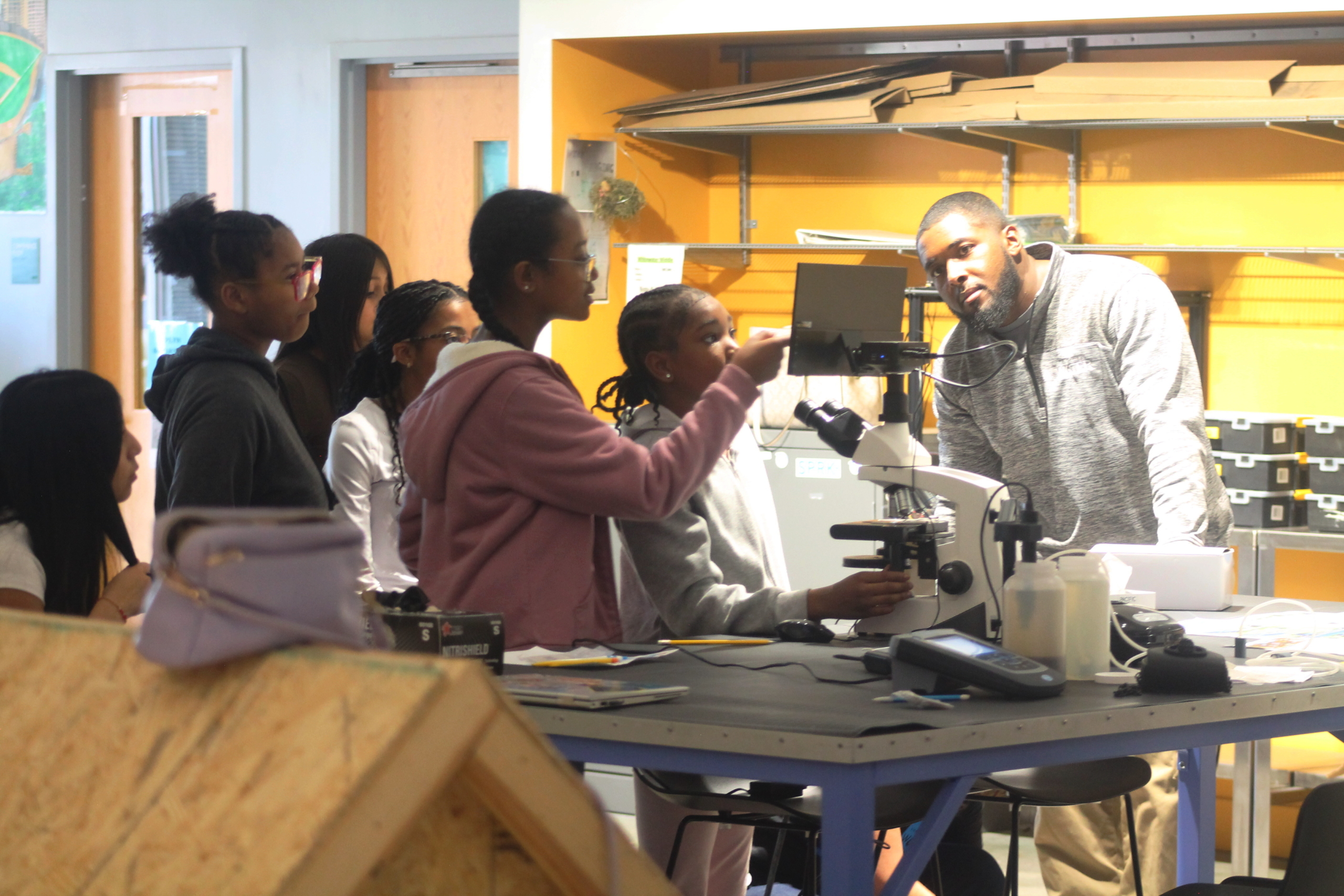 Students gather around a microscope screen