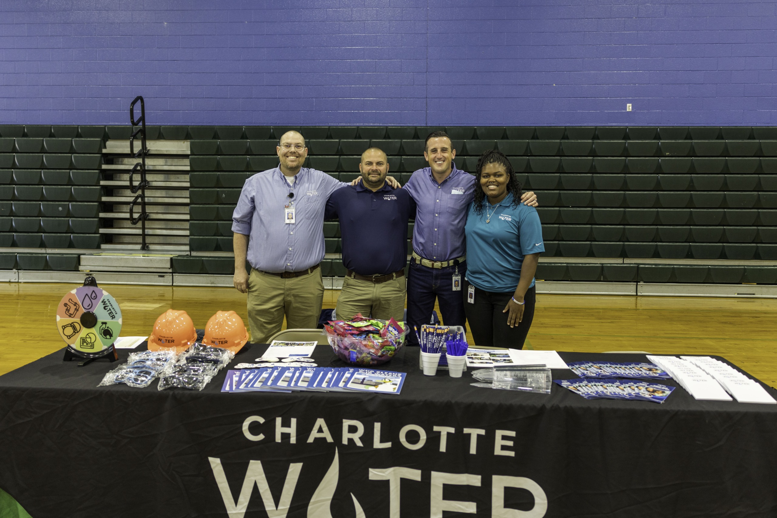 Charlotte Water employees smile behind a table set with prizes and handouts for students.