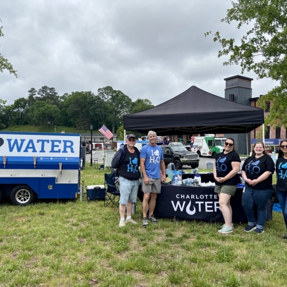 Charlotte Water staff in front of a tent and water wagon